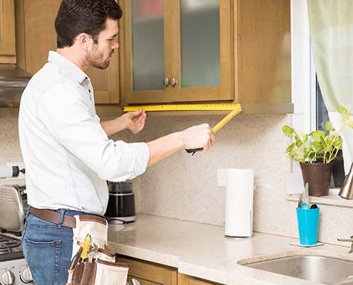 Custom cabinet maker measuring for kitchen cabinetry intallation