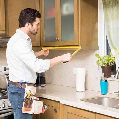 Custom cabinet maker measuring for kitchen cabinetry intallation